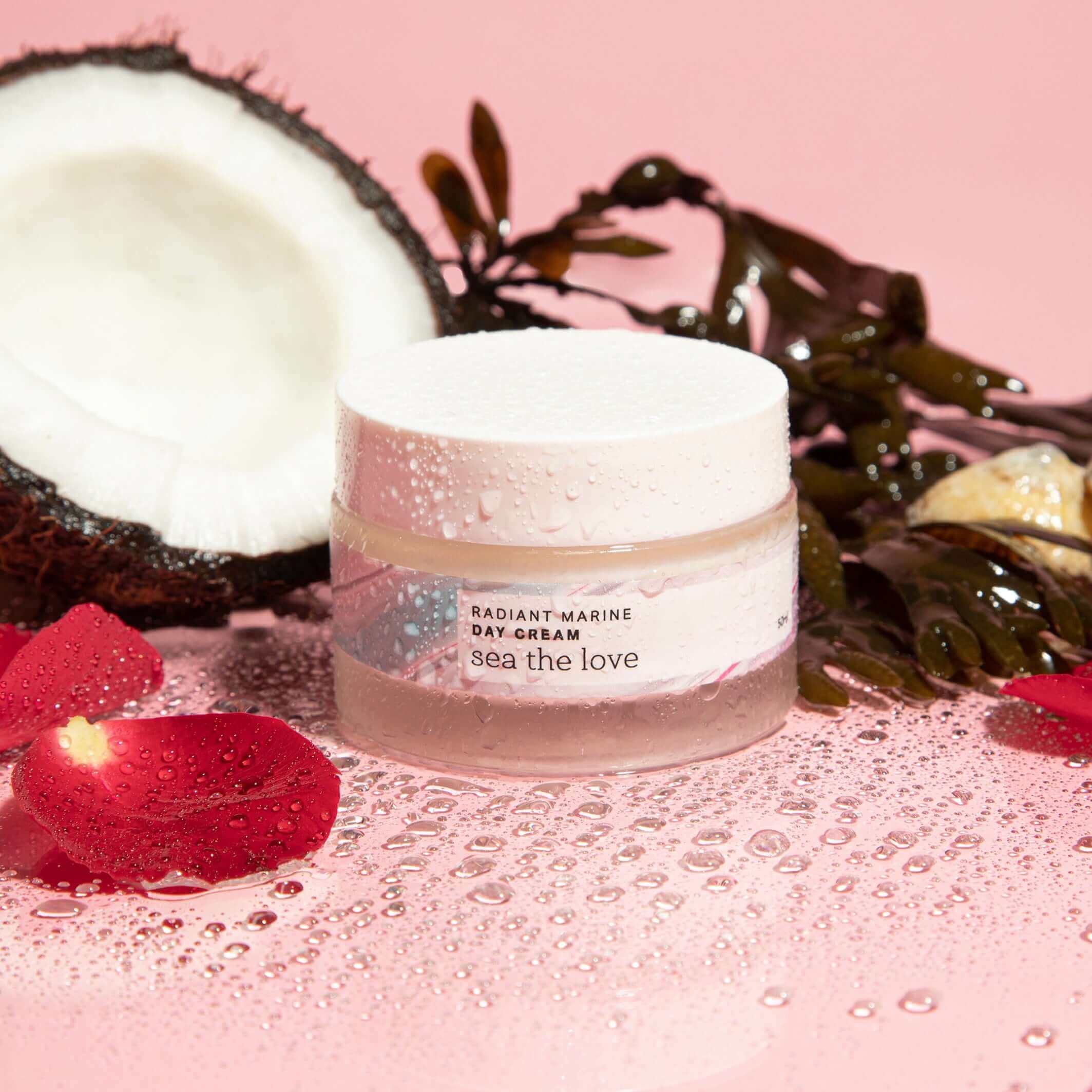 Radiant Marine Day Cream surrounded by coconut, seaweed, rose petals, and water to represent the natural ingredients of this ocean-inspired moisturiser.