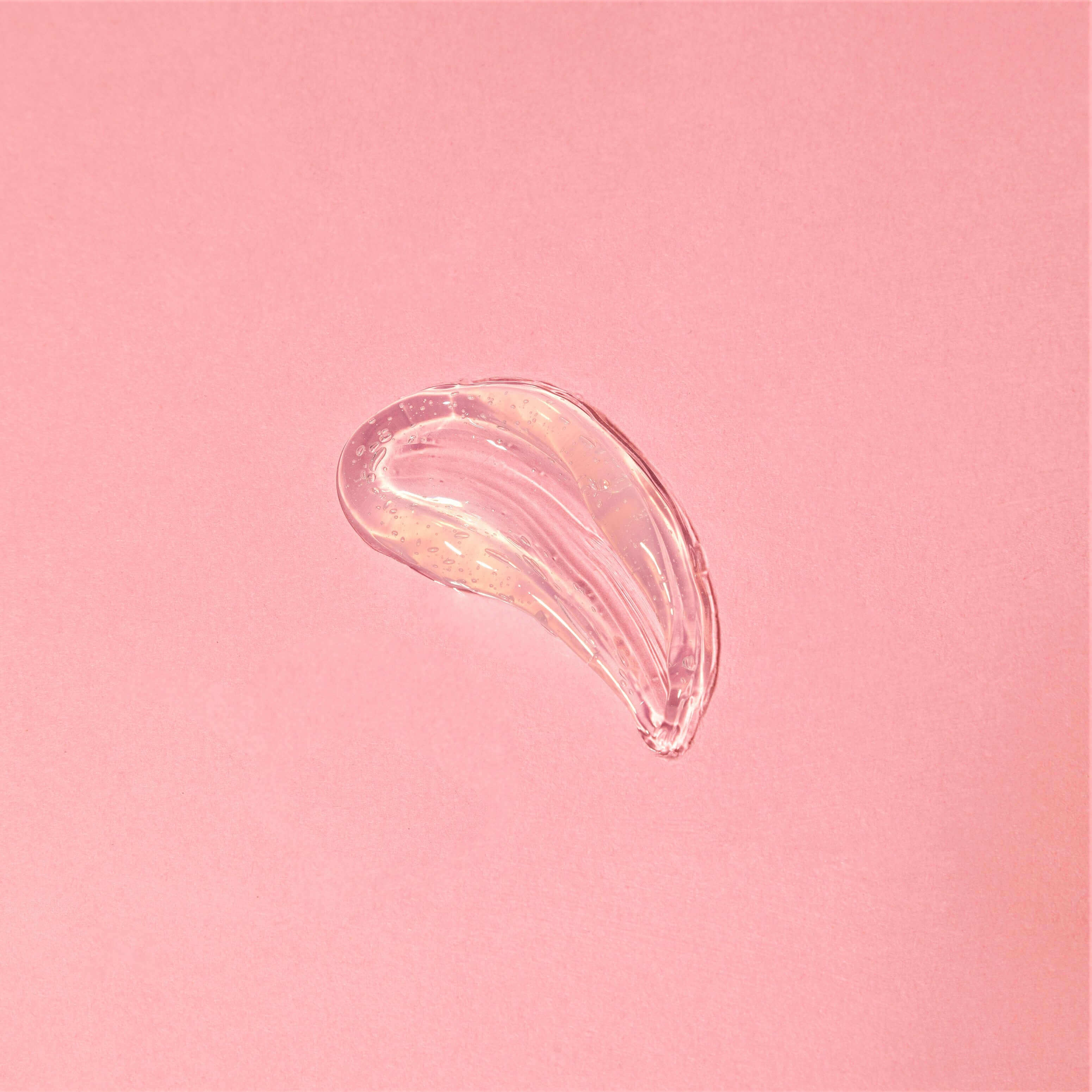 Swatch of Beachy Clean Melting Cleanser on a pink background showcasing its smooth, gel consistency.