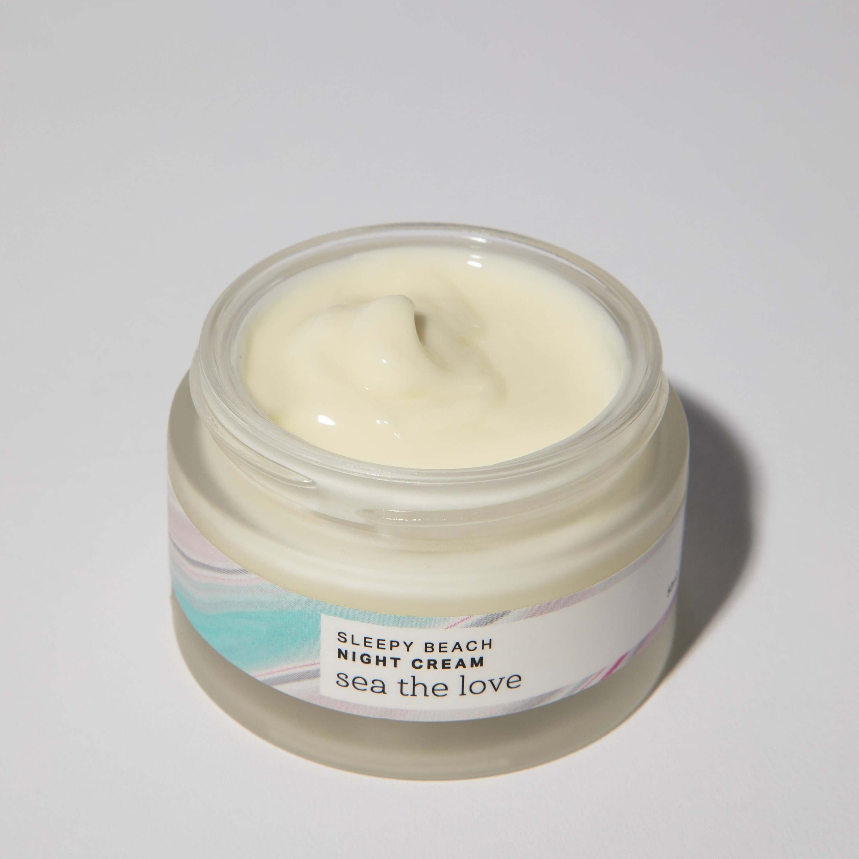 A open jar of Sleepy Beach Night Cream, showcasing its creamy texture, infused with sea minerals and green microalgae.