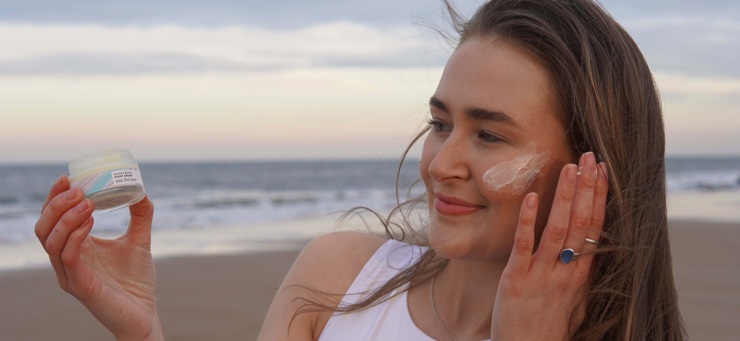 Woman using Sleepy Beach Night Cream by the sea