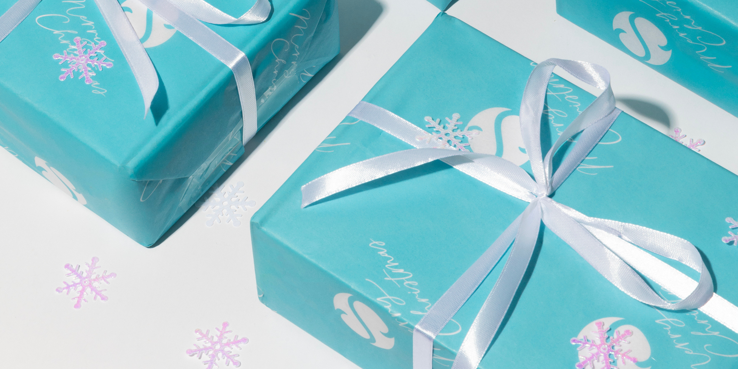 a box wrapped in sea the love branded Christmas gift wrapping, with a white bow