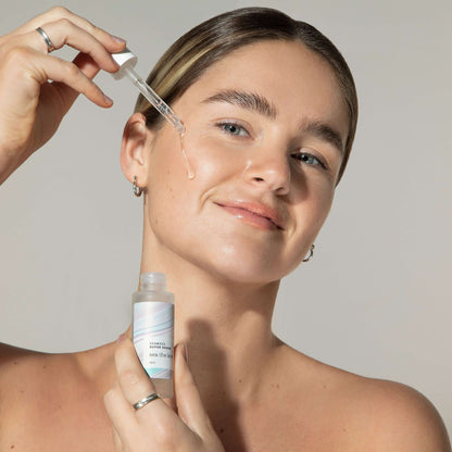 Woman applying Seaweed Super Serum with dropper for enhanced skin moisture and firmness using marine magnesium, red seaweed, and hyaluronic acid.