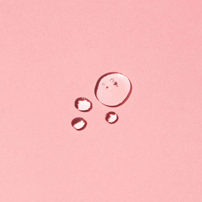 Close-up of Seaweed Super Serum drops on pink background showcasing consistency of the hydrating seaweed serum formula with natural ingredients.